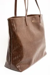 Bolso tipo shopper color marrón de cuero sintético con diseño trenzado. Cuenta con doble asa de hombro y placa metálica con el logo de la marca en el frente.