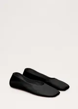Zapato plano tipo chatita, de color negro, confeccionado en piel de ovino con diseño minimalista y puntera cuadrada.
