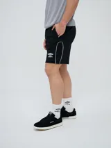 Bermuda deportiva Umbro modelo Veliz para hombre, color negro con detalles en blanco, cordón ajustable en la cintura y logo bordado en la pierna izquierda.