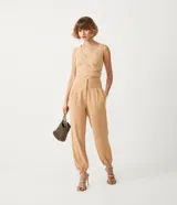 Pantalón zanahoria color beige de crepé con cinturilla ancha, botones con forma de león y pinzas delanteras.