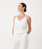 Blusa blanca de poliéster con escote en pico, tirantes finos ajustables y corte cruzado.