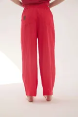 Pantalón de lino color beige, de silueta relajada, tiro medio-alto, cintura elastizada con cordón ajustable, bolsillos laterales y bolsillos traseros.