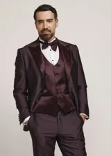 Traje formal de tres piezas en tono tostado brillante, compuesto por saco con solapas en contraste, pantalón de corte recto y chaleco a juego, acompañado de moño.