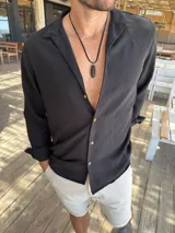 Camisa de manga larga color negro, confeccionada en tela liviana y fresca, con cuello clásico y botones frontales en contraste.