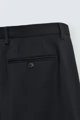 Pantalón de traje regular fit confeccionado en tejido de lana. Presenta bolsillos frontales, bolsillos traseros de vivo con botón y cierre frontal con cremallera y botón.