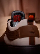 Zapatillas Hush Puppies edición limitada inspiradas en Luke Skywalker, con diseño en tonos tierra, beige y marrón. Presentan una combinación de cuero y descarne, con detalles de Star Wars grabados en el lateral y en la lengüeta, y cordones con detalles en naranja.