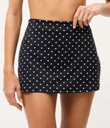 Short pollera deportivo negro con estampa de lunares blancos, confeccionado en microfibra con cintura alta y short interno integrado.