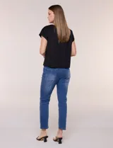 Blusa de silueta recta confeccionada en crepe elastizado, color negro, con escote a la base destacado con una delicada tira aplicada de perlas y cuentas, mangas cortas dollman y ruedo recto.