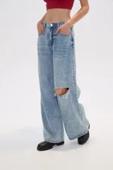 Pantalón de jean celeste de corte ancho con rotura en la rodilla.