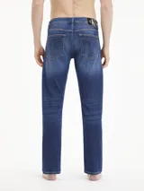 Jeans de hombre Calvin Klein de corte slim, color azul oscuro con efecto desgastado y lavado en la parte frontal de los muslos. Presenta cinco bolsillos y cierre de cremallera.