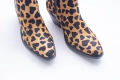 Texana de caña corta con diseño de animal print en color fucsia y negro. Presenta un taco bajo y aberturas laterales.