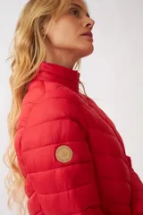 Campera puffer color rojo con cuello alto, cierre frontal completo y diseño acolchado con costuras horizontales en forma de V.