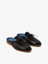 Zueco de cuero negro estilo náutico, con costuras expuestas en contraste, detalle de lazo en el empeine y suela de goma.