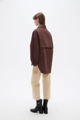 Campera marrón de manga larga confeccionada en algodón, con cuello camisero, cierre frontal con botones a presión y puños elásticos fruncidos.
