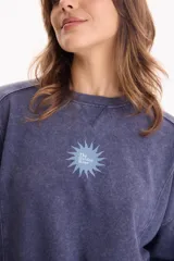 Buzo deportivo sin frisa color azul con efecto lavado, cuello redondo, mangas largas y estampa pequeña en el pecho con diseño de sol y texto.