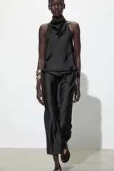 Top blanco satinado con cuello halter y escote fluido. Cierre en la espalda con botones.