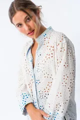 Camisa blanca con broderie y mangas largas con puños en color azul.