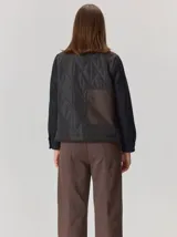 Campera de diseño híbrido con frente acolchado en color tostado, solapas y cuello en tejido de lana con patrón de cuadros tipo príncipe de gales, y mangas en paño de lana color azul marino. Cuenta con cierre frontal de botones.