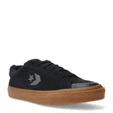 Championes Converse de corte bajo, confeccionados en gamuza negra con el logo de la estrella y el chevrón en el lateral. Presentan una suela de goma color caramelo (gum) y puntera reforzada.
