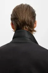 Abrigo de corte clásico confeccionado en tejido afieltrado con mezcla de lana. Presenta solapas de muesca, cierre frontal con tres botones y bolsillos laterales insertados al bies. Diseño de silueta estructurada con mangas forradas.