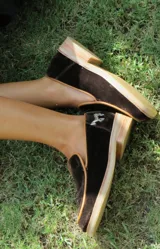 Mocasines de diseño clásico con puntera almendrada y talón cerrado, confeccionados en terciopelo marrón con ribetes y suela de goma con tacón bajo. Cuentan con un detalle de aplique metálico en forma de caballo en el lateral.