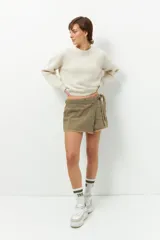 Short pollera de jean prelavado color negro, con lazo en uno de sus laterales y detalle de flecos en las terminaciones.