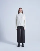 Sweater de lana color crema con cuello alto y mangas largas. Posee detalles calados en la parte superior del pecho y diseño acanalado en puños y ruedo.