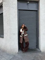 Chaleco largo de eco cuero color marrón con interior y detalles de corderito en solapas y bolsillos frontales.