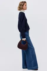 Pantalón de jean de tiro alto con corte wide leg y piernas amplias. Presenta diseño con raya frontal marcada, cierre con botón oculto, bolsillos laterales al bies y bolsillos traseros decorativos.