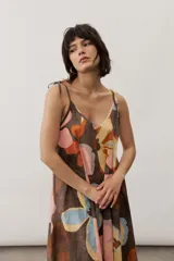 Vestido midi de tirantes ajustables con lazo en los hombros, escote en V y diseño amplio con estampado floral abstracto en tonos marrones, rosados, celestes y amarillos.