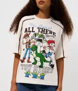 Remera de algodón color crema con cuello redondo y mangas cortas con costuras desplazadas en contraste. Presenta un estampado frontal grande con los personajes de la película Toy Story.