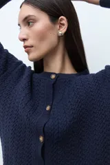 Cardigan de punto con textura de tejido estructurado, color bordó, con cuello redondo, cierre frontal de botones y mangas largas.