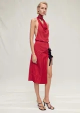 Top de punto fino color rojo con diseño de cuello halter drapeado y espalda descubierta. Presenta un cierre de botones en el cuello y un bajo asimétrico.