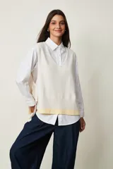 Chaleco de punto color beige claro con escote en V, sin mangas y diseño abierto en los laterales con ajuste de cintas para atar.