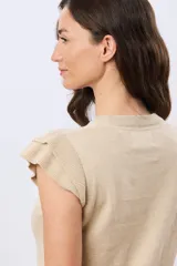 Remera tejida de algodón en color beige, de cuello redondo, sin mangas y con detalles de volados estructurados en los hombros.