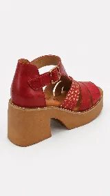 Sandalias de cuero color suela, con plataforma alta y taco ancho. Presentan tiras cruzadas en el empeine con mix de texturas y cierre de hebilla metálica en el tobillo.