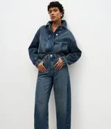Pantalón de jean modelo carrot con cintura alta, corte holgado en caderas y piernas que se estrechan hacia el tobillo. Confeccionado en denim de algodón con lavado medio, cuenta con cinco bolsillos funcionales, cierre frontal con botón y cremallera, y trabillas para cinturón.