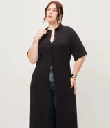 Vestido chemise midi color negro confeccionado en viscosa, de corte recto y holgado. Cuenta con cuello camisero, mangas cortas y cierre frontal con botones al tono.