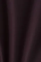 Top de manga larga color bordó, confeccionado en punto suave, con escote redondo y hombros caídos. Presenta un detalle de nudo y tiras laterales en la cintura.