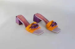 Sandalias tipo sueco color amarillo, con taco ancho y aplique de cadena en el empeine.