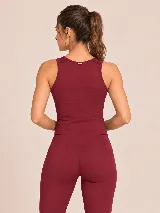Conjunto deportivo de dos piezas color bordó, compuesto por un top básico sin mangas de cuello redondo y una calza acampanada de tiro alto con aberturas en los tobillos.