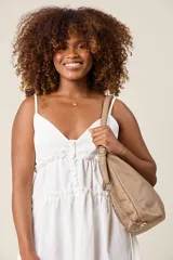 Cartera tipo hobo de ecocuero color beige, con textura granulada, cierre superior con cremallera, doble asa corta y correa larga regulable con cadena decorativa.