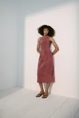 Vestido midi de piel color rosado, con cuello redondo y diseño sin mangas. Presenta costuras marcadas y cierre en la espalda con cremallera oculta.