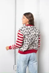 Saco de punto con diseño combinado, presentando un estampado de animal print en el frente y mangas a rayas horizontales en rojo y beige. Posee cuello redondo, cierre frontal con botones y terminaciones en tejido acanalado de color rojo.