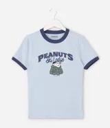 Remera de algodón color celeste con cuello y bordes de mangas en color azul marino. Presenta estampa frontal con el personaje Snoopy vestido con campera puffer y la inscripción Peanuts Ski Lodge.