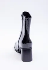 Botín negro de charol con caña media, punta cuadrada, cierre lateral y tacón bloque.