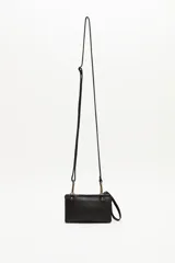 Cartera pequeña tipo bandolera de cuero vacuno negro, con detalle frontal de lentejuelas doradas. Cuenta con correa larga ajustable y extraíble, y una manija lateral corta para llevar en la muñeca.
