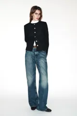 Blazer de corte entallado con cuello redondo, manga larga y hombreras. Presenta cierre frontal con botones dorados y una textura sutil en la tela.