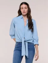 Camisa de lyocell color celeste, con cuello camisero, cierre frontal con botones y detalle de nudo en el ruedo. Presenta mangas tres cuartos abullonadas con puños elásticos.