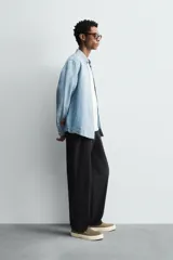 Camisa de corte regular fit confeccionada en denim ligero de algodón con efecto lavado. Presenta cuello solapa con botones, manga larga con puños abotonados, cierre frontal de botones y un bolsillo plastrón en el pecho.